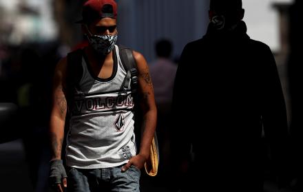 En la imagen, un hombre con mascarilla camina por una calle de Quito (Ecuador).