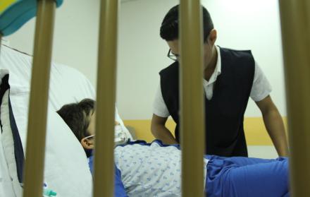 Atención. Un niño se recupera de un tratamiento hospitalario, mientras recibe la visita de un conocido.