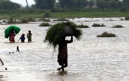 Varias personan vadean un área inundada tras las fuertes lluvias en Sanghar, Pakistán, el 23 de agosto de 2022.