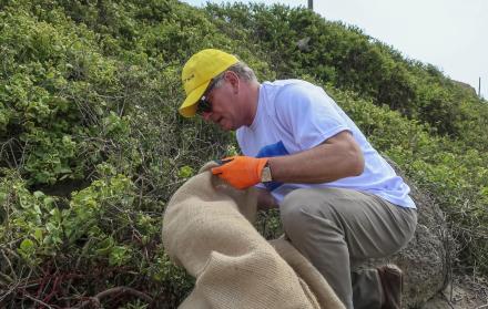 Voluntarios realizan una jornada de limpieza recogiendo basura, el 25 de noviembre del 2022, en las playas de Puerto Cayo (Ecuador).
