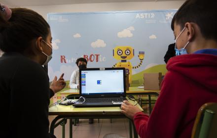 Dos niños manejan un robot por ordenador en un colegio español.