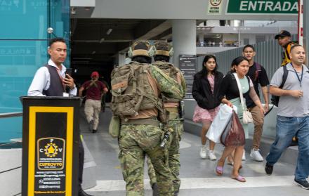 Soldados ecuatorianos persiguen hoy a un presunto delincuente mientras ciudadanos evacúan a pocas cuadras de la sede del canal de televisión TC