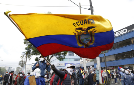 Fotografía de archivo en donde se ve a una persona que levanta una bandera de Ecuador.