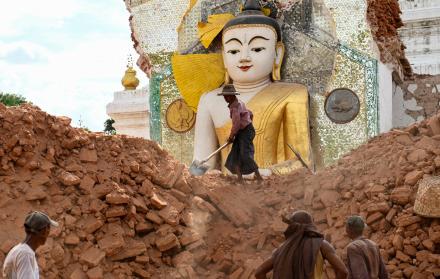 Fotografía del 12 de abril de 2025 muestra a un hombre retirando escombros alrededor de una dañada estatua de Buda