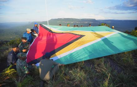 hombres desplegando una bandera de Guyana en la montaña Pakrampa, en la aldea de Arau, región Esequibo (Guyana).