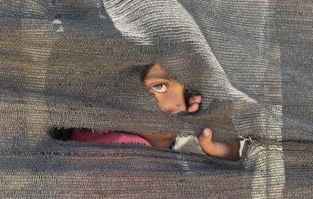 Una niña se asoma tras una tienda improvisada en el puerto en la Ciudad de Gaza, donde miles de personas desplazadas por los ataques israelíes han encontrado refugio, el 20 de mayo de 2025.
