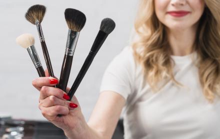sonriendo-visagiste-mujer-sosteniendo-cepillos-cosmeticos