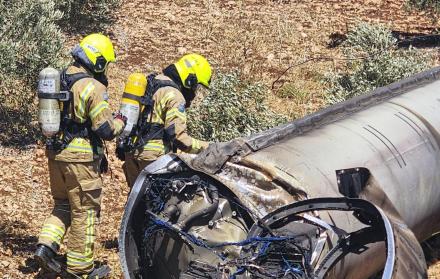Dos bomberos observan los restos de un misil balístico iraní en un olivar de Galilea.