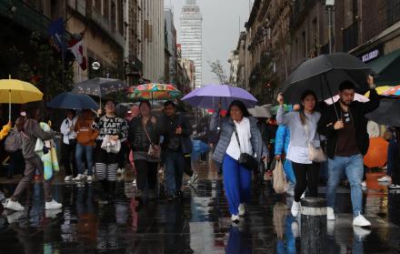 Personas se protegen de la lluvia con sombrillas en México