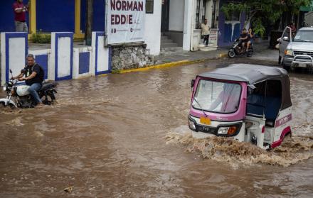 Conductor de moto taxi que circula por una calle inundada