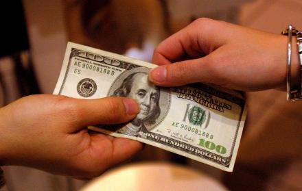 Dos manos sosteniendo un billete que puede interpretarse como recibo de remesas