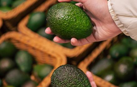 una-mujer-elige-un-aguacate-en-una-tienda-de-comestibles