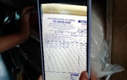 Una mano sostiene la foto de una factura.