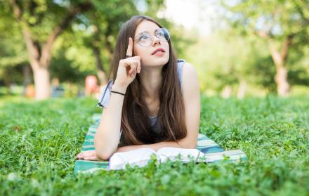 mujer-hermosa-joven-se-acuesta-en-campo-verde-y-lee-el-libro