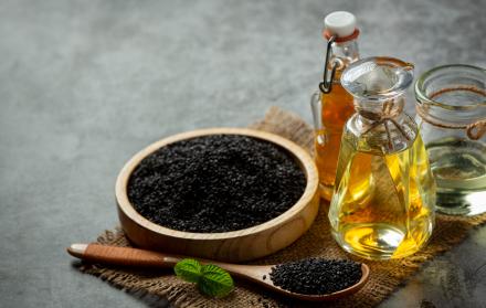 aceite-de-sesamo-y-semillas-de-sesamo-negras-crudas-sobre-fondo-oscuro