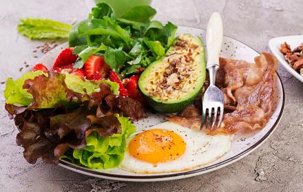 plato-con-una-comida-de-dieta-ceto-huevo-frito-tocino-aguacate-rucula-y-fresas-keto-desayuno