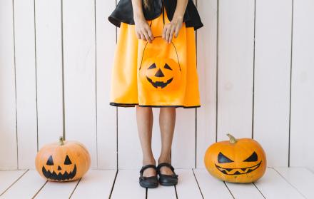 piernas-de-nina-sosteniendo-la-cesta-de-halloween-con-calabazas-en-los-lados