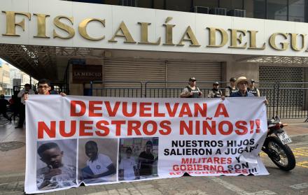 Archivo del 23 de diciembre de 2024 que muestra dos personas sosteniendo un cartel en los exteriores de la Fiscalía Provincial del Guayas