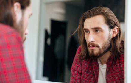 hombre-en-camisa-cuadros-mirando-al-espejo-en-casa
