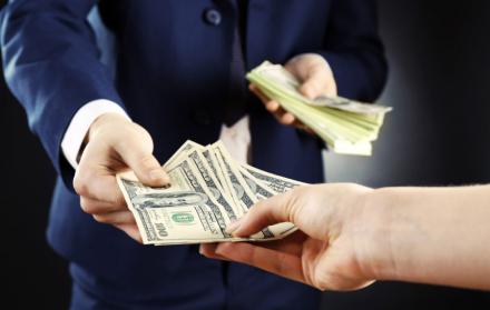 MANO DE EJECUTIVO ENTREGANDO DINERO O BILLETES A OTRA PERSONA.