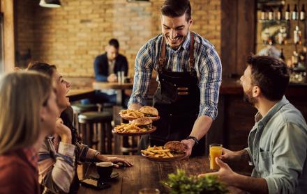 camarero-feliz-sirviendo-comida-un-grupo-de-amigos-alegres-en-un-pub