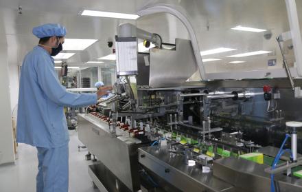 Hombre opera una maquinaria en industria farmacéutica