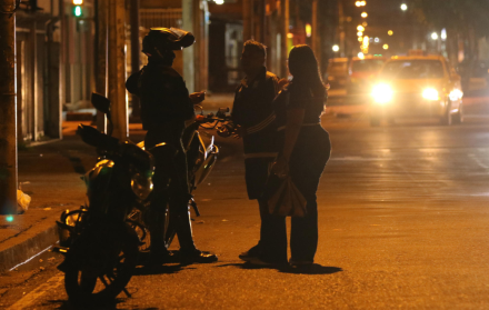Un integrante de la Policía de Ecuador conversa con ciudadanos tras el toque de queda este domingo, en Guayaquil