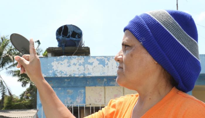 Janeth Maenza muestra su tanque de agua derretido por el calor. Su casa está a seis metros del incendio.