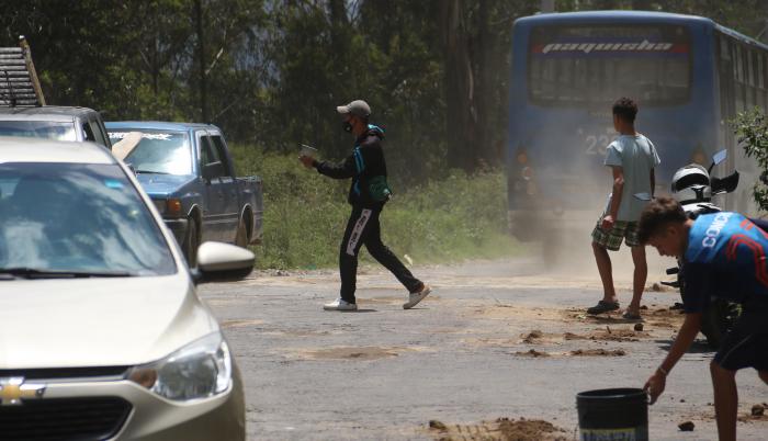 Los extranjeros aprovechan los enormes baches en la vía para rellenarlos y ganar algo de dinero.