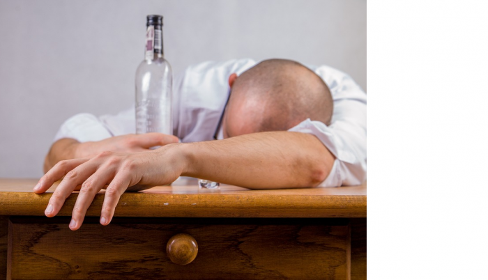 Hombre junto a botella de alcohol