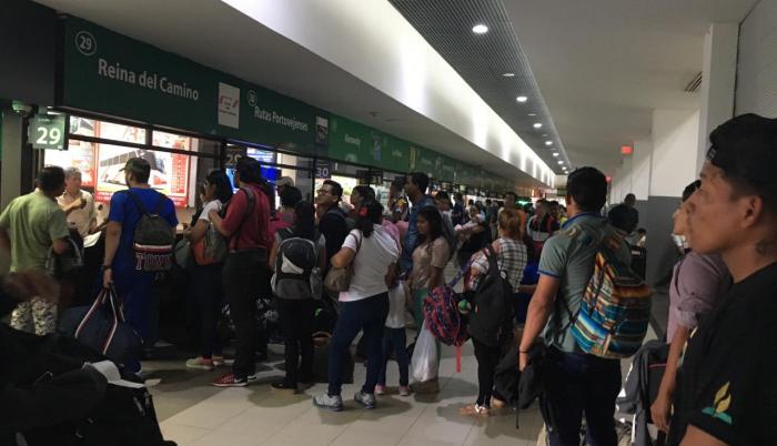 Pasajeros forman largas filas en la terminal terrestre para comprar un boleto de autobús.