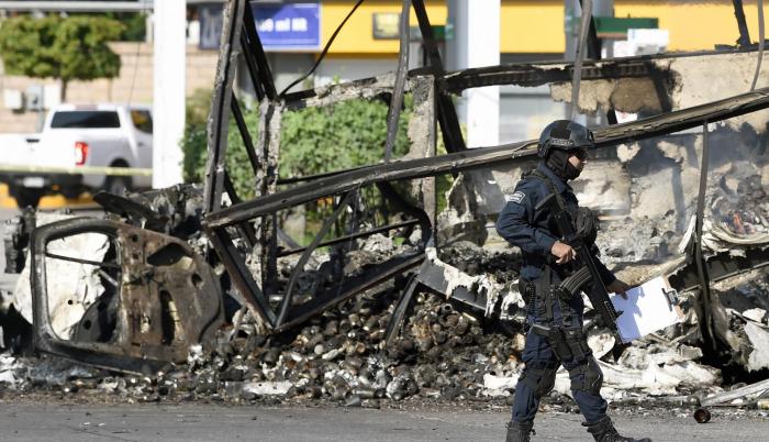 México. Un policía pasa junto a un vehículo quemado luego del ataque.