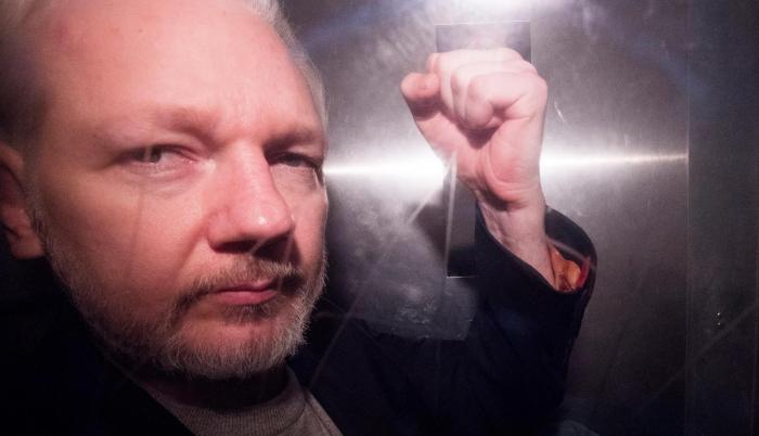 Condena. Julian Assange, con pelo corto y barba recortada, eleva el puño desafiante a la salida de la audiencia.
