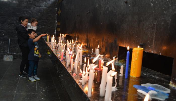 Los feligreses con sus velas primero oran en la gruta de la Virgen del Rosario de Agua Santa.
