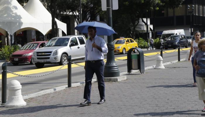 Centro. Un ciudadano se protege del sol mientras camina por la calle Pedro Carbo y su intersección con 9 de Octubre.