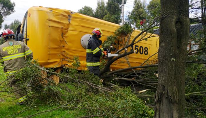 Tras el impacto, un bus escolar quedó volcado sobre la vía.