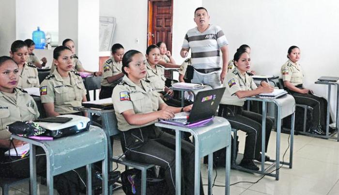 En el salón. Las aspirantes atienden al profesor, quien enseña una de las materias con ayuda de un proyector.