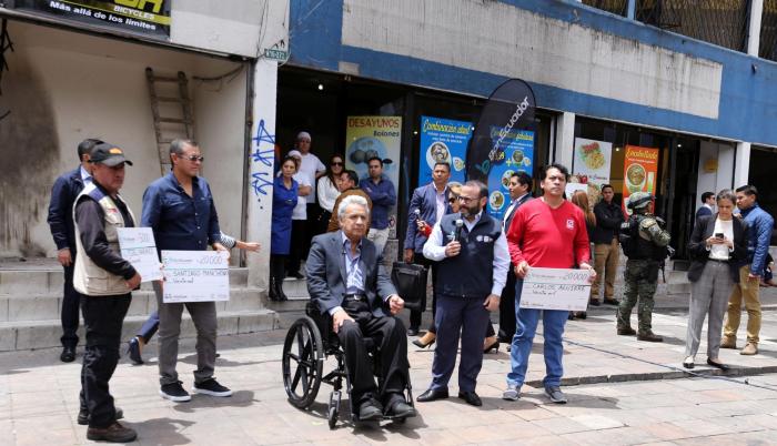 Ayuda. El presidente posa entre los comerciantes afectados por la violencia, quienes exhiben sus cheques de Banecuador por hasta 20 mil dólares.