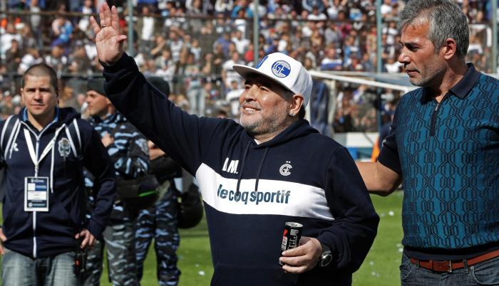 La estrella del fútbol argentino Diego Maradona saluda al público junto al presidente Gabriel Pellegrino.