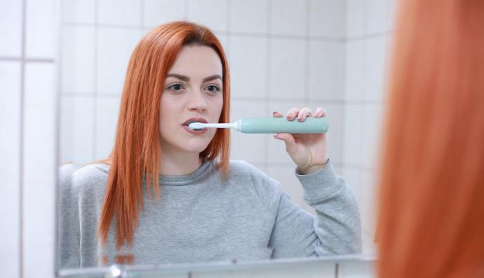 Mujer cepillándose los dientes.