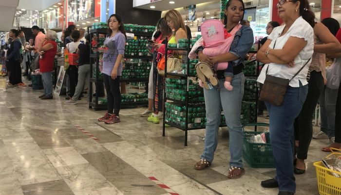 Un grupo de personas espera para pagar sus compras en un local de Caracas.