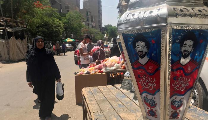 Una mujer observa un farol de colores, típico del mes sagrado de Ramadán, en el barrio islámico de El Cairo, que este año son diferentes ya que lucen el rostro del futbolista egipcio Mohamed Salah, que alumbra las calles y hogares del país.