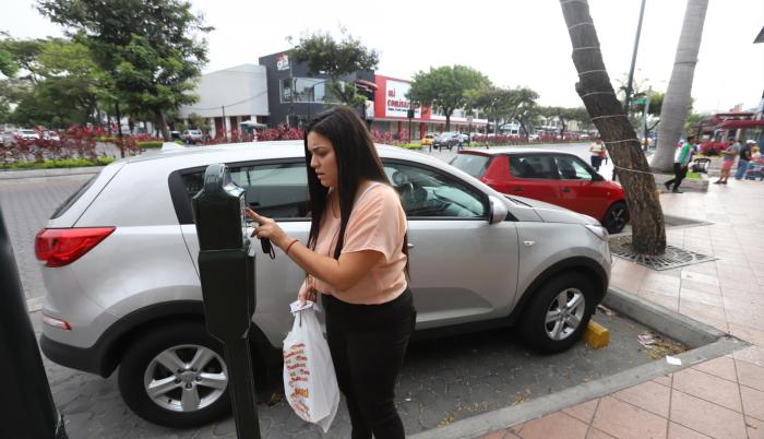 Gestión. Emily Avilés coloca unas monedas al parquímetro antes de comprar en un local de Plaza Triángulo.