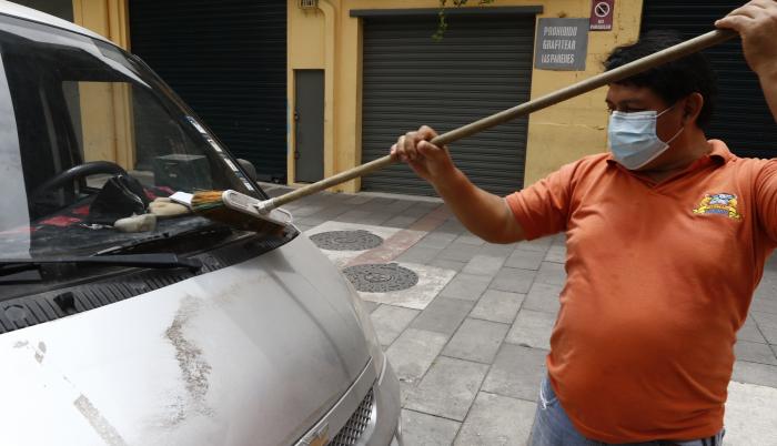 Un ciudadano de Guayaquil retira las cenizas del volcán en un barrio de Guayaquil.