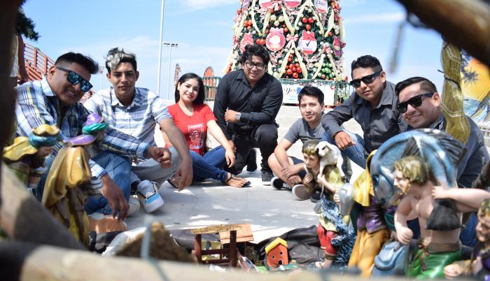 7 de los 12 cantantes junto a un pesebre en el malecon