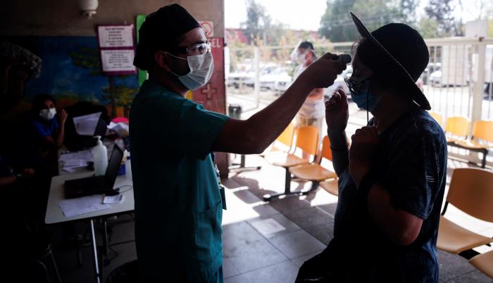 Un enfermero toma la temperatura a una mujer antes de su ingreso a un centro de salud en Santiago (Chile)