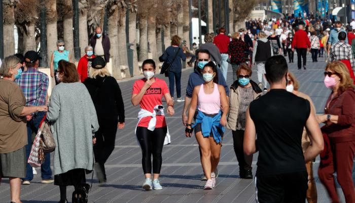 Decenas de personas por el paseo de la playa de la Malvarrosa de Valencia, España.