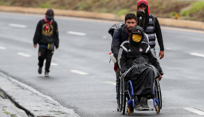 Ciudadanos venezolanos, uno de ellos con discapacidad, transitan por una carretera cercana a Quito (Ecuador).