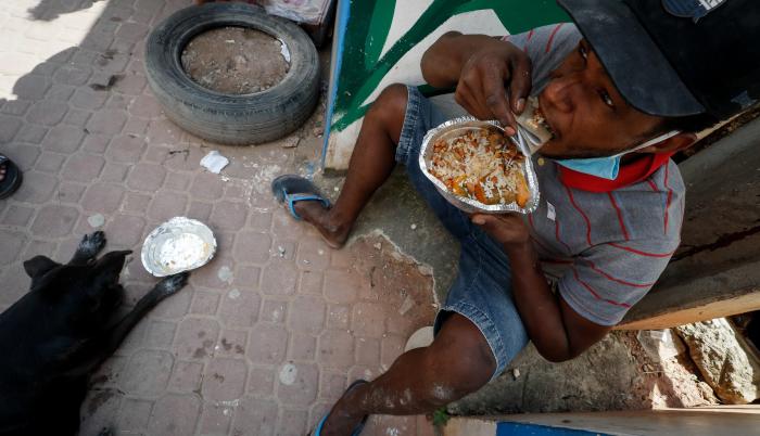 Henrique Silva, de 22 años, almuerza tras recibir una donación de comida en la calle da Paz, el 2 de abril de 2021 en la favela de Paraisópolis, en Sao Paulo (Brasil).