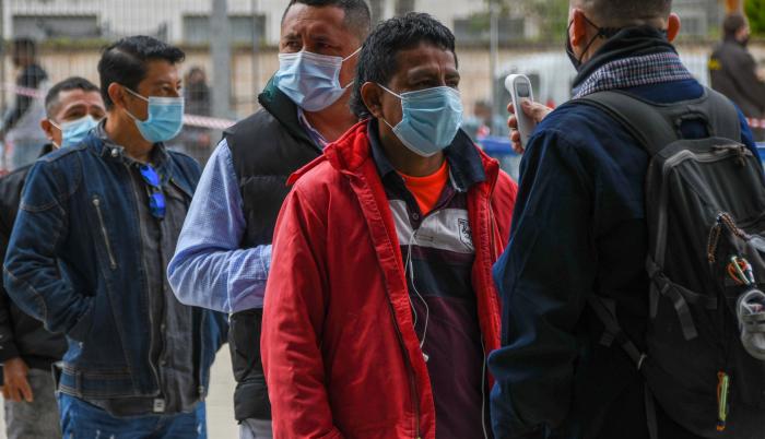 Un empleado le toma la temperatura a una ciudadana ecuatoriana residente en España vota en la segunda vuelta de las elecciones presidenciales de su país este domingo en el Palma Arena de Palma de Mallorca.
